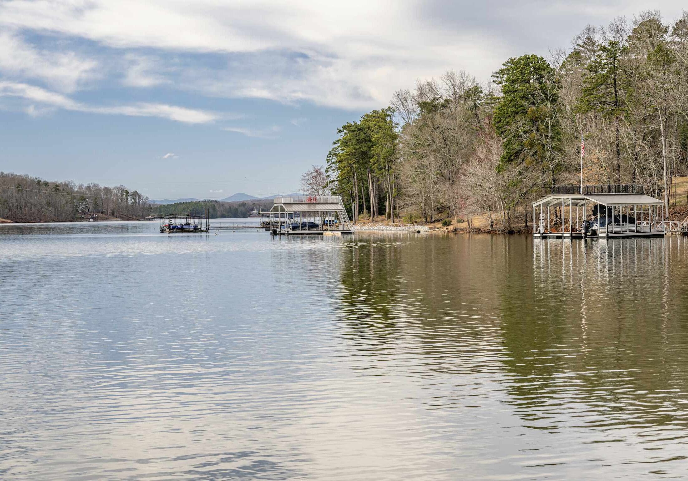 Boat docks along the wooded shoreline of Lake Lanier near Gainesville, Georgia, with calm water and distant hills.